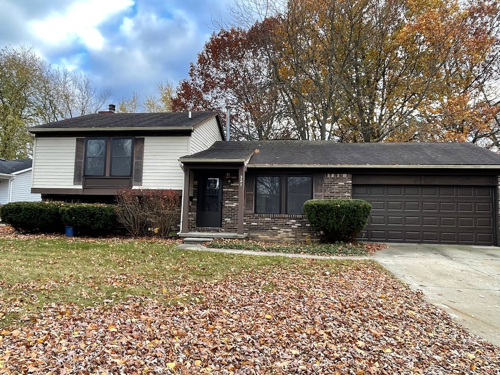 tri-level home featuring a garage and a front lawn