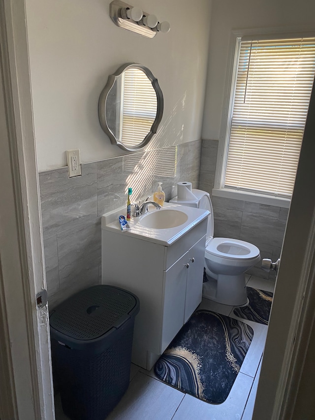 bathroom featuring toilet, vanity, tile patterned floors, and tile walls