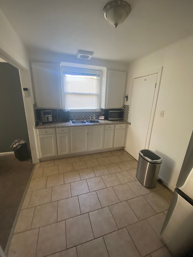 kitchen with white cabinets, decorative backsplash, and sink