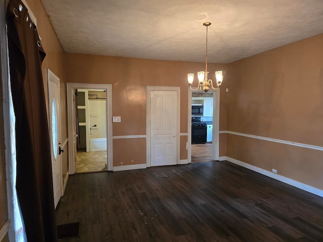 unfurnished dining area with a notable chandelier, dark hardwood / wood-style flooring, and a textured ceiling