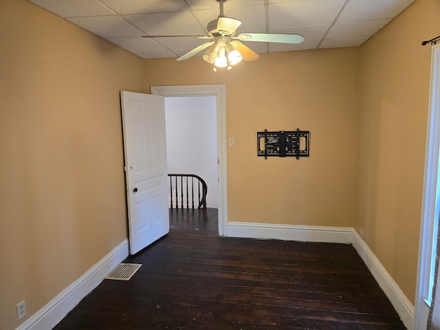 spare room featuring ceiling fan, a drop ceiling, and dark wood-type flooring