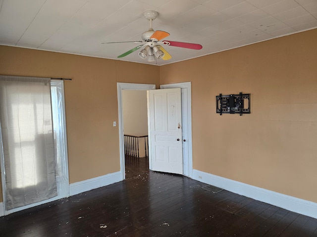 spare room featuring ceiling fan, a healthy amount of sunlight, and dark wood-type flooring