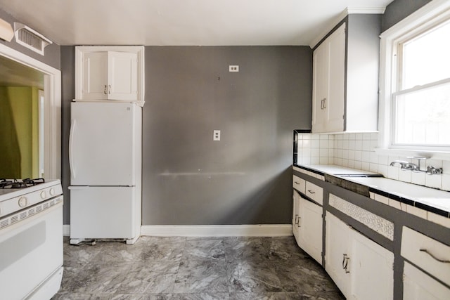 kitchen with tile counters, white cabinetry, sink, and white appliances