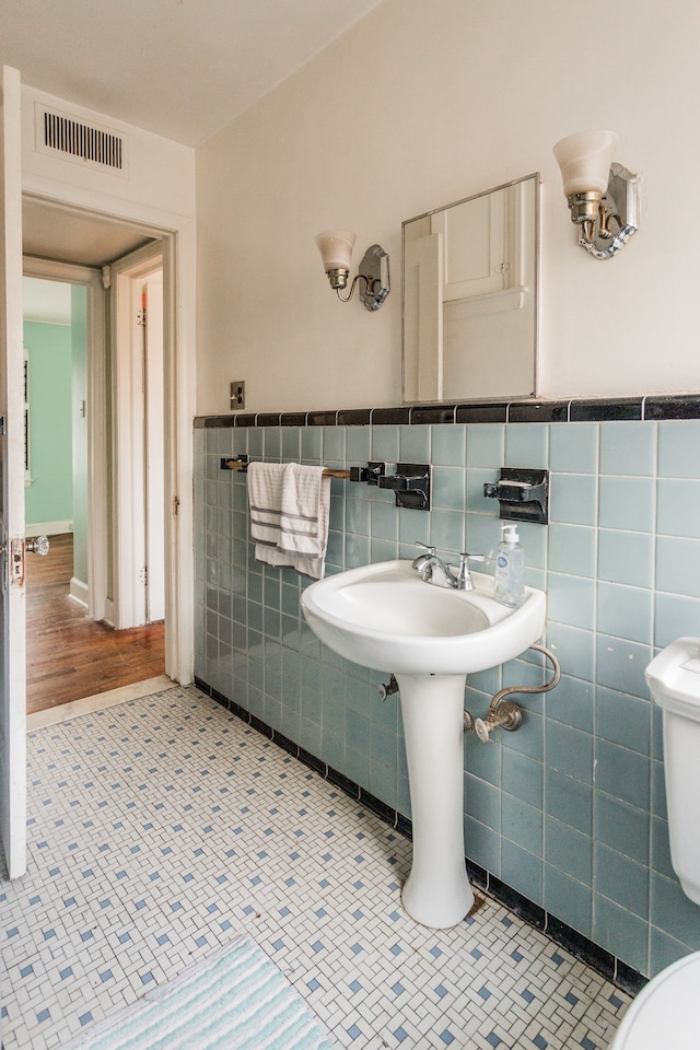 bathroom featuring tile patterned flooring, toilet, and tile walls