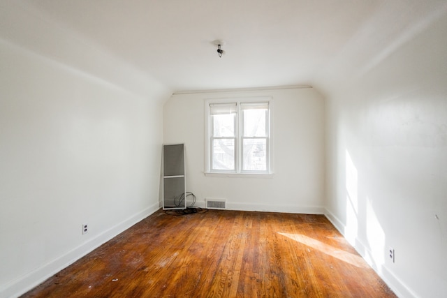 additional living space with hardwood / wood-style floors and vaulted ceiling