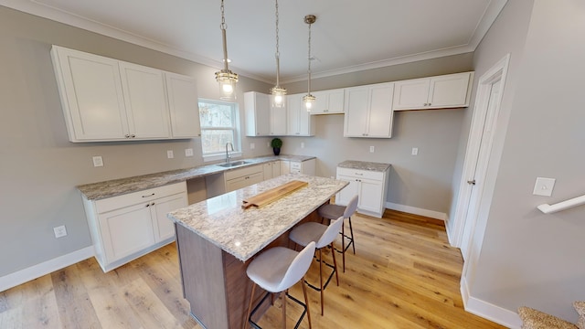 kitchen with white cabinets, a kitchen island, sink, and light hardwood / wood-style flooring