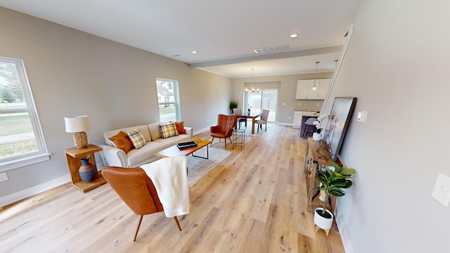 living room featuring plenty of natural light, a notable chandelier, and light wood-type flooring