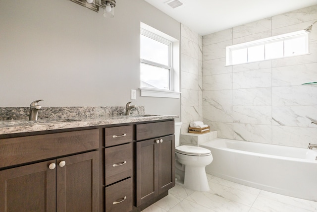 full bathroom with tiled shower / bath, vanity, and toilet