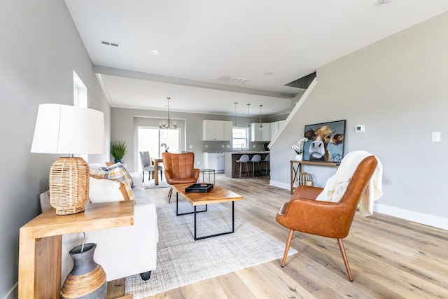 living room with a notable chandelier and light hardwood / wood-style floors