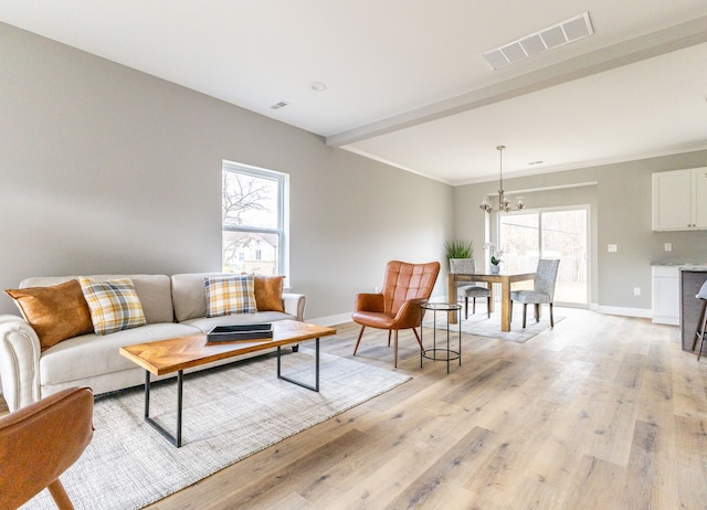 living room with a wealth of natural light, light hardwood / wood-style flooring, a chandelier, and ornamental molding