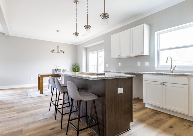 kitchen featuring hanging light fixtures, white cabinets, a kitchen island, and plenty of natural light