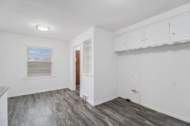 laundry area featuring dark wood-style flooring, visible vents, and baseboards