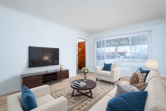 living area with light wood-style flooring and arched walkways