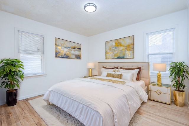 bedroom featuring a textured ceiling, baseboards, and wood finished floors