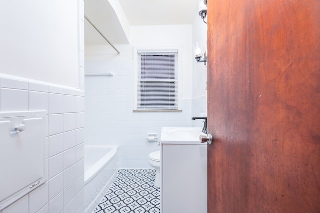 bathroom with tile patterned flooring, toilet, vanity, tile walls, and wainscoting