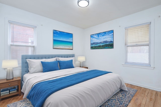 bedroom featuring multiple windows, baseboards, and wood finished floors