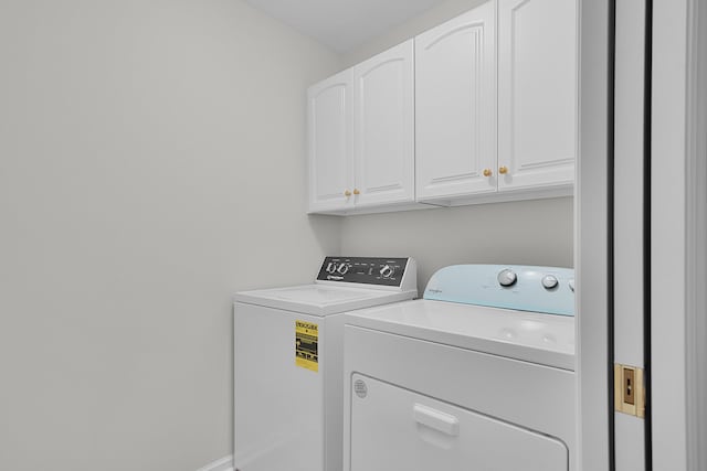 washroom with washing machine and clothes dryer and cabinets