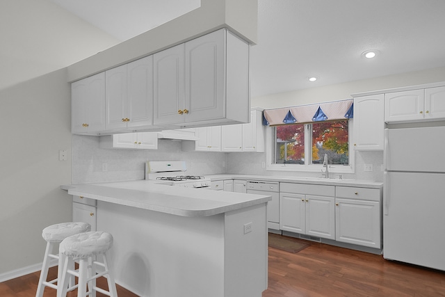 kitchen featuring a breakfast bar, dark hardwood / wood-style flooring, white cabinets, and white appliances