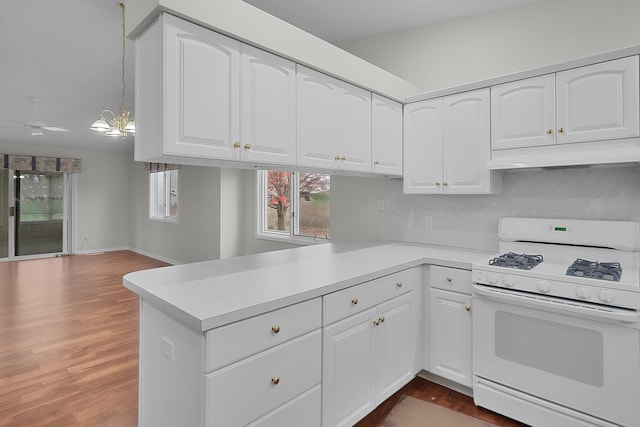 kitchen featuring kitchen peninsula, white gas range oven, decorative light fixtures, dark hardwood / wood-style floors, and white cabinetry