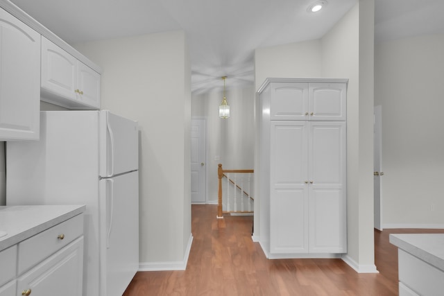 kitchen with white cabinets, white fridge, pendant lighting, and light hardwood / wood-style floors