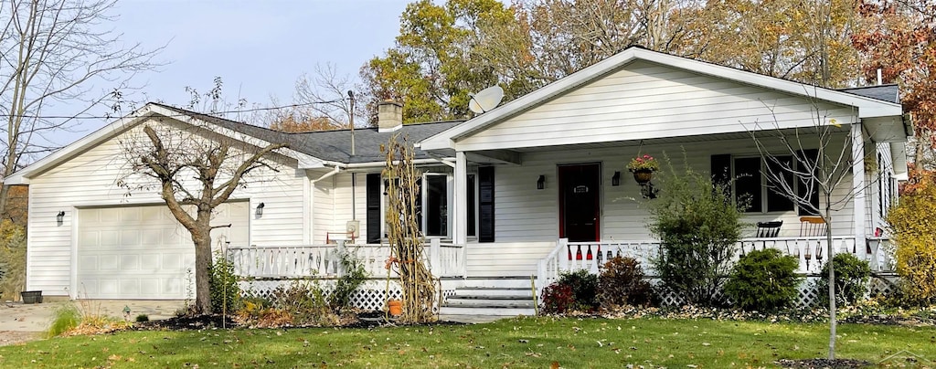 bungalow-style home with covered porch, a front yard, and a garage