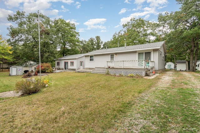 rear view of property featuring a wooden deck, a yard, and a storage unit