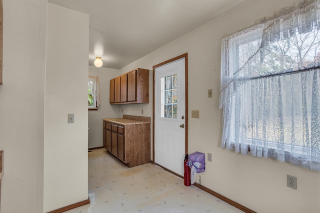 kitchen featuring light floors, brown cabinets, and baseboards