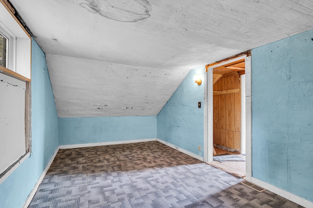 additional living space featuring baseboards, carpet floors, and vaulted ceiling