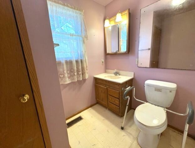 half bathroom featuring visible vents, baseboards, toilet, tile patterned floors, and vanity