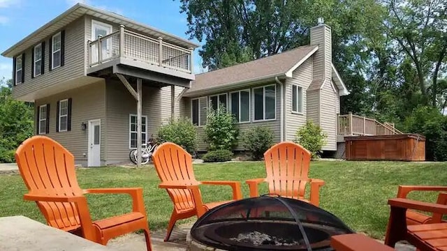 back of house with a lawn, an outdoor fire pit, and a wooden deck