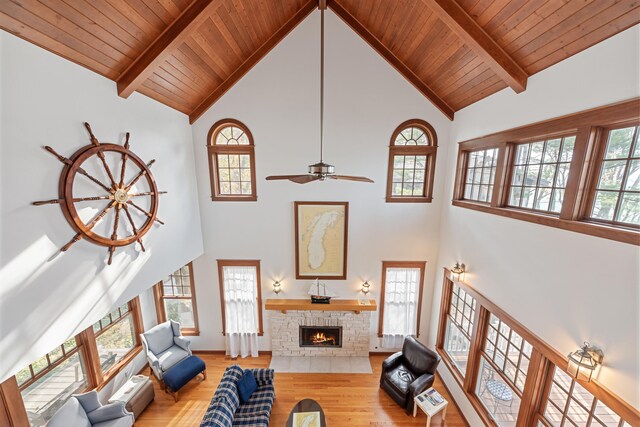 5722 Dunham Path, Stevensville, MI 49127 - living room featuring high vaulted ceiling, wood finished floors, wood ceiling with exposed beams, a stone fireplace, and a ceiling fan