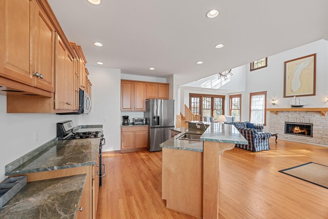 5722 Dunham Path, Stevensville, MI 49127 - kitchen with stainless steel appliances, light wood-style flooring, a breakfast bar, a sink, and a fireplace