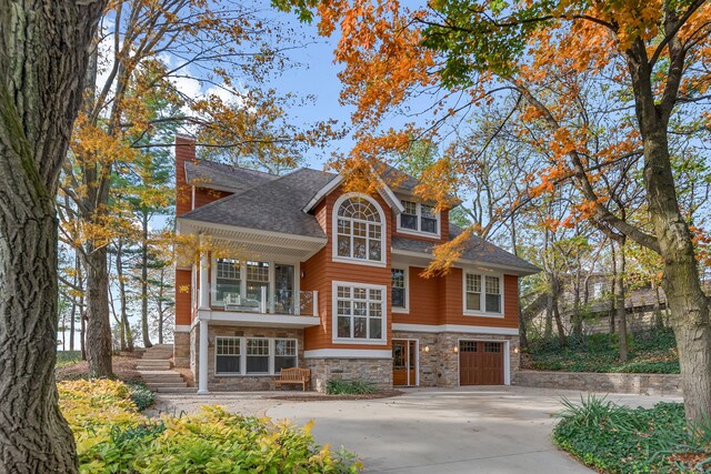 5722 Dunham Path, Stevensville, MI 49127 - view of front facade featuring stone siding, concrete driveway, a garage, a balcony, and a chimney