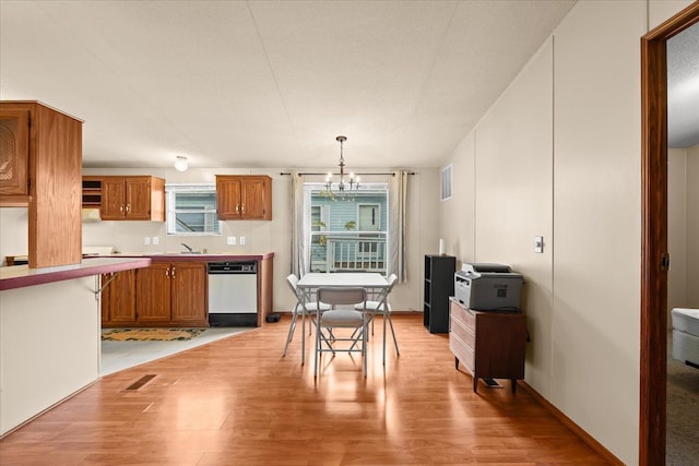 kitchen with dishwasher, an inviting chandelier, hanging light fixtures, and light hardwood / wood-style flooring