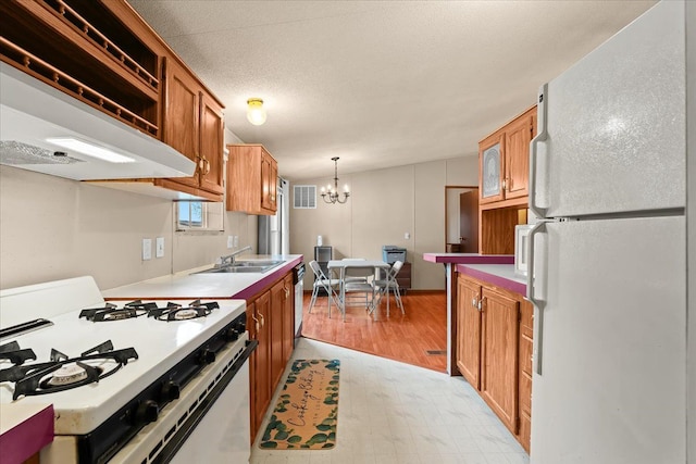 kitchen with white appliances, an inviting chandelier, sink, decorative light fixtures, and light hardwood / wood-style floors