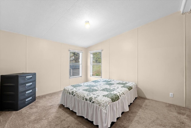 bedroom with carpet flooring, a textured ceiling, and vaulted ceiling