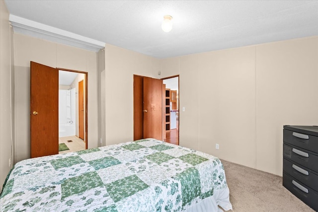 bedroom with light colored carpet, a textured ceiling, and ensuite bath