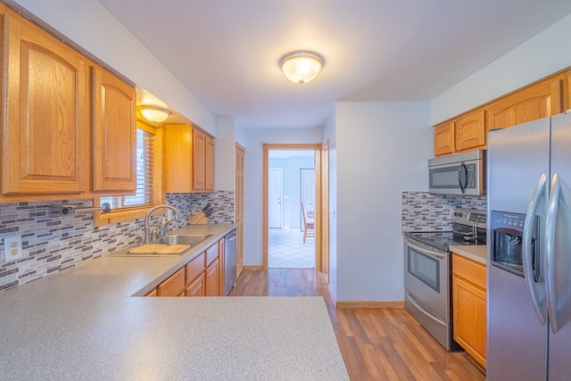 kitchen with stainless steel appliances, light hardwood / wood-style flooring, tasteful backsplash, and sink