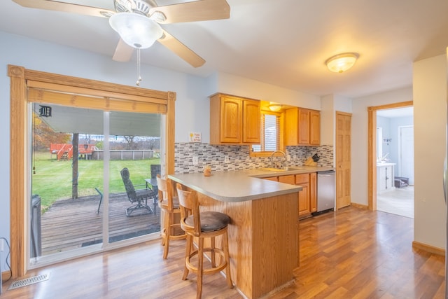 kitchen featuring a breakfast bar, sink, light hardwood / wood-style flooring, tasteful backsplash, and kitchen peninsula