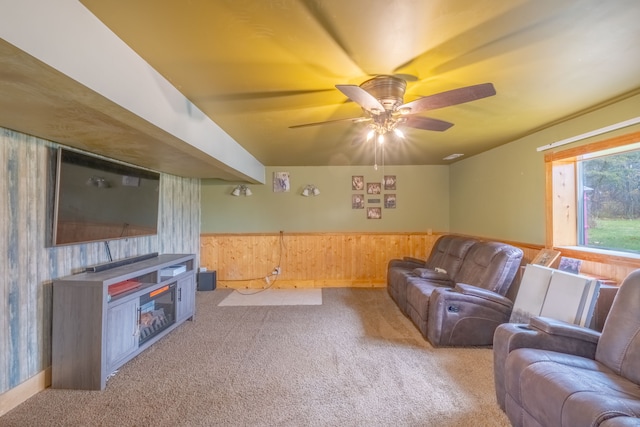 carpeted living room featuring ceiling fan and wooden walls