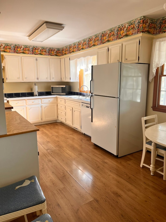 kitchen featuring white cabinetry, plenty of natural light, light hardwood / wood-style floors, and white appliances