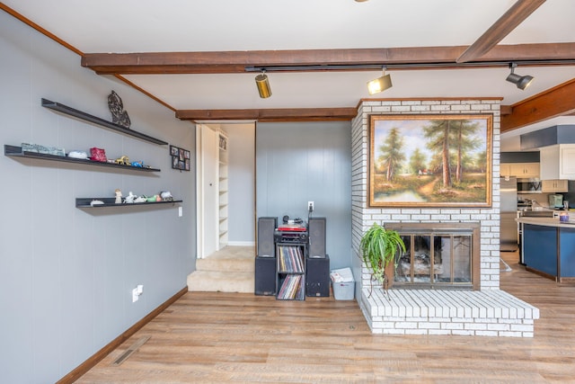 living room featuring beam ceiling, light wood-type flooring, a fireplace, and wooden walls