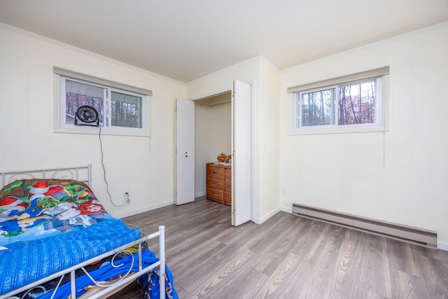 bedroom featuring crown molding, a baseboard radiator, and hardwood / wood-style flooring