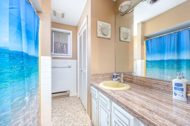 bathroom with tile patterned flooring, vanity, baseboard heating, and tile walls