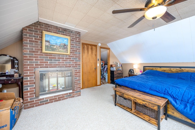 carpeted bedroom featuring a brick fireplace, vaulted ceiling, and ceiling fan