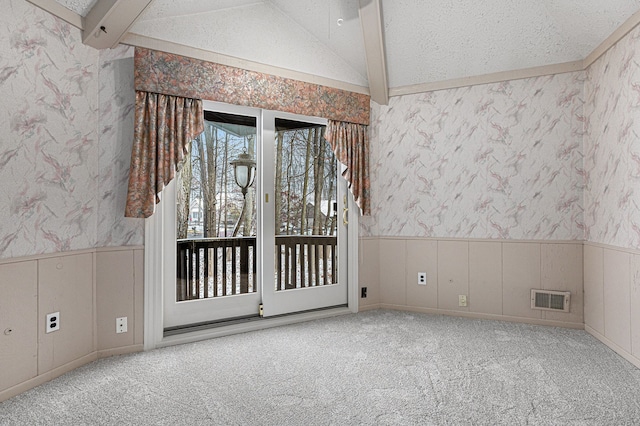 carpeted empty room featuring vaulted ceiling with beams and a textured ceiling