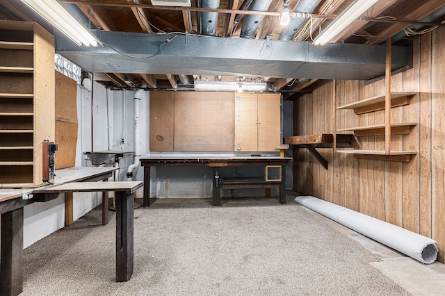 basement featuring a workshop area, wood walls, and carpet floors