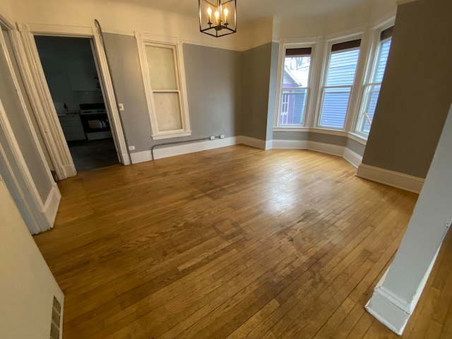 unfurnished dining area featuring light hardwood / wood-style floors and an inviting chandelier