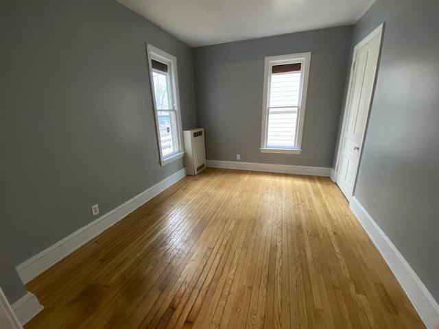 spare room with radiator heating unit and light wood-type flooring