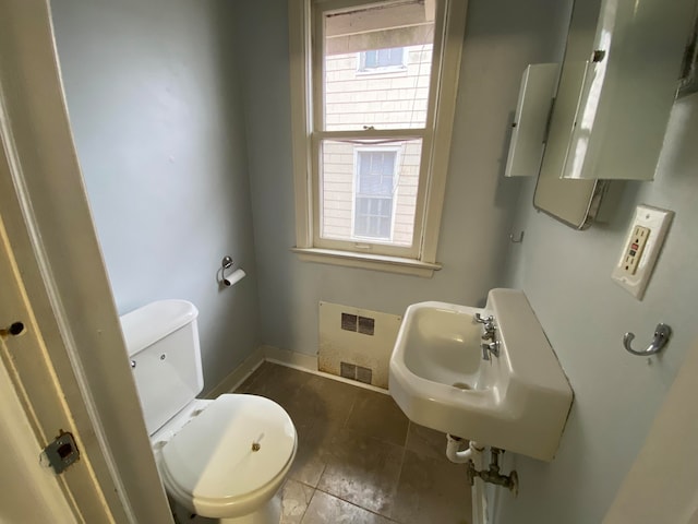 bathroom with radiator heating unit, toilet, tile patterned floors, and sink